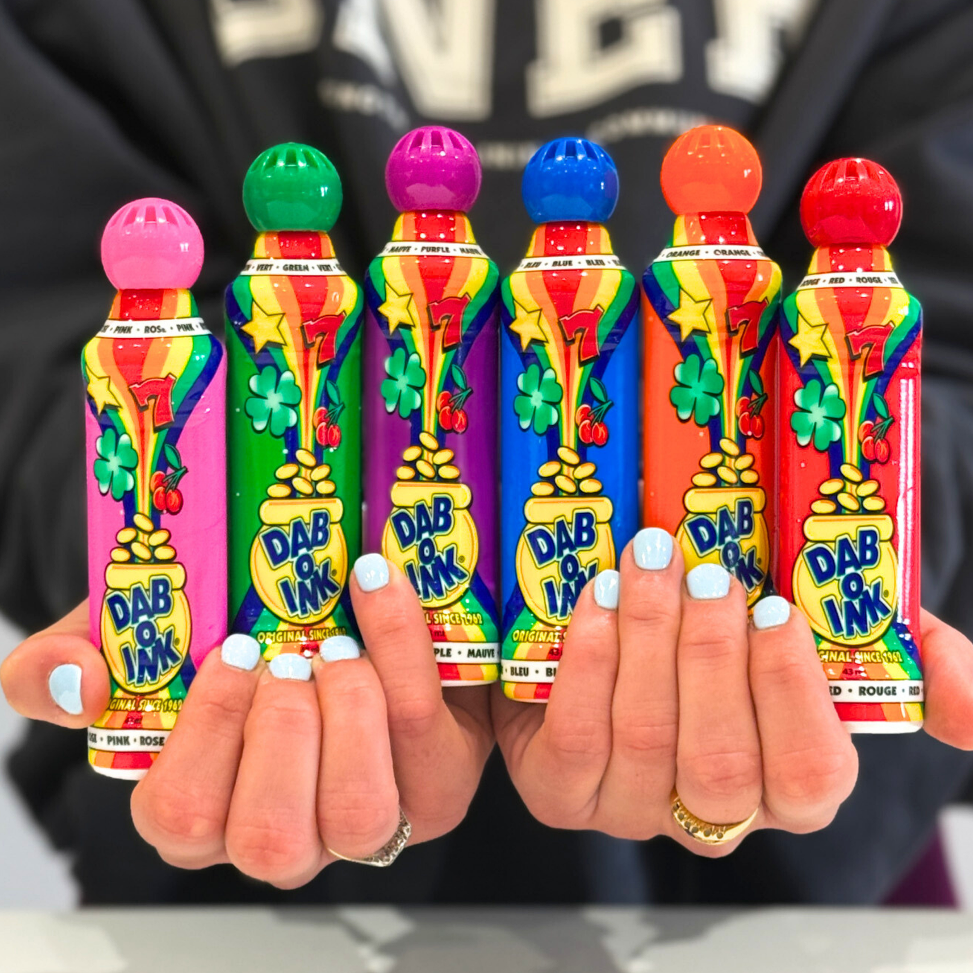 A person holding up six Dab O ink Bingo Dabbers